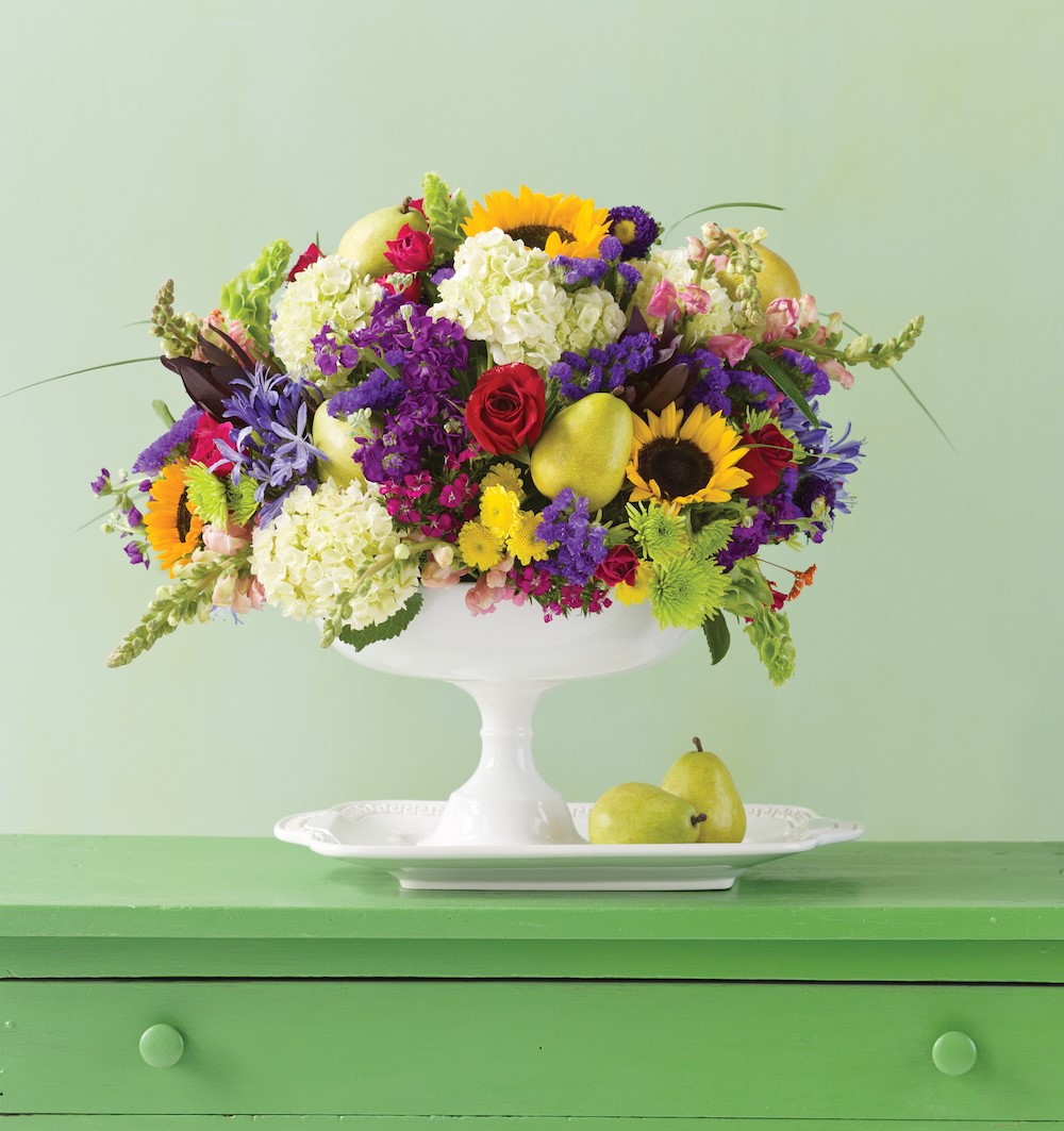 pear and wildflower bouquet in a white footed vase