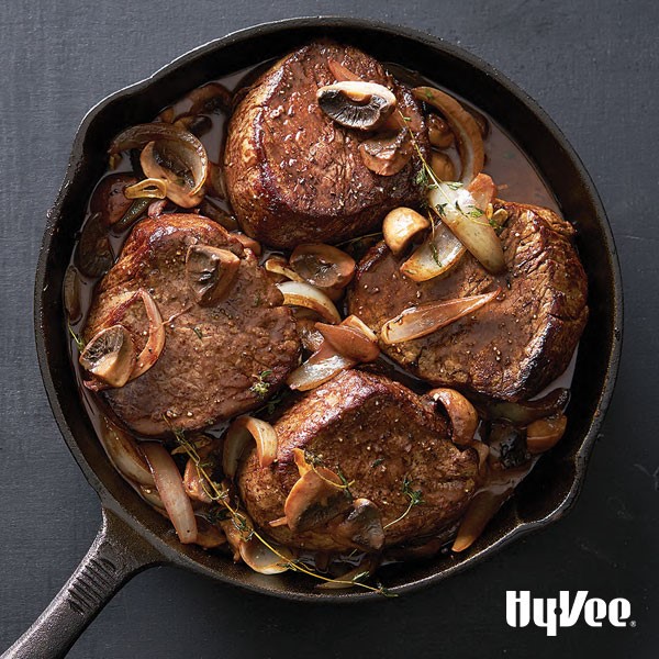 Pan seared filets with onions and mushrooms in cast-iron pan