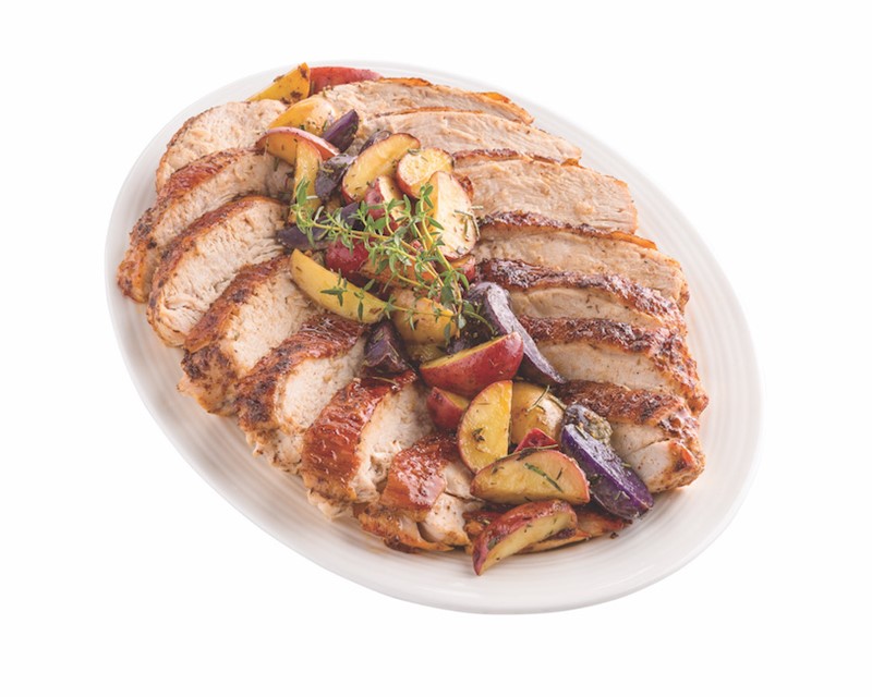 Platter of sliced turkey breast meat with roasted potatoes on top
