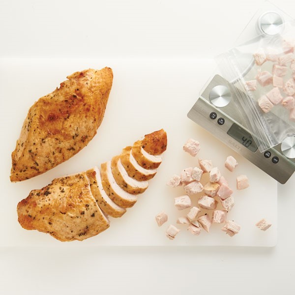Roasted and spiced turkey breasts sliced and cubed on cutting board with scale