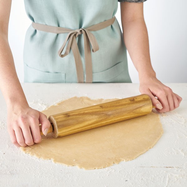 Using a rolling pin to roll out pie crust on lightly floured surface
