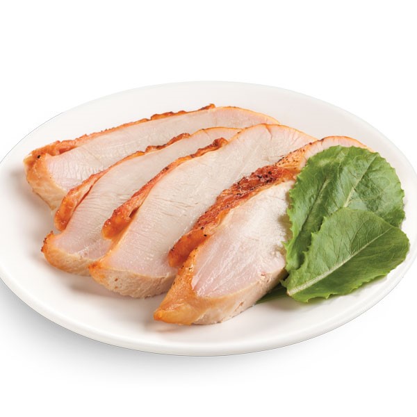 Roasted and sliced turkey breast on a white plate with spinach leaves for garnish