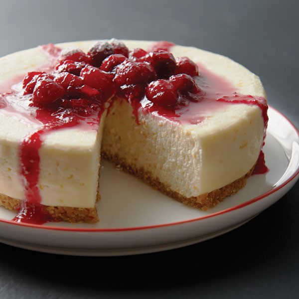 Plate of cheesecake layered with graham cracker crust, cheesecake filling and raspberries