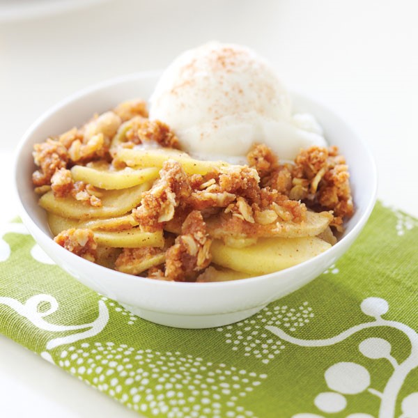Bowl of apple crisp served with a scoop of vanilla ice cream topped with cinnamon
