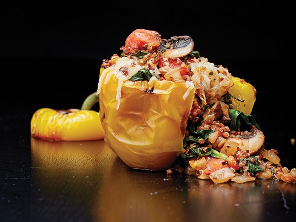 Yellow bell pepper filled with onion, tomato, quinoa, spinach and herbs
