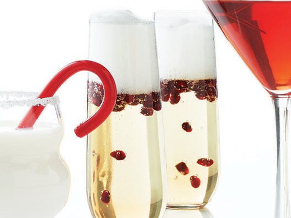 Two glasses of bubbly champagne cocktail, filled with pomegranate seeds