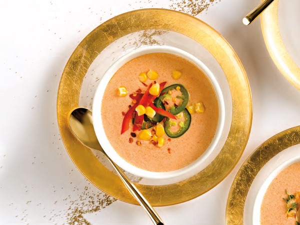 Bowl of lobster bisque garnished with red bell pepper, corn and jalapenos